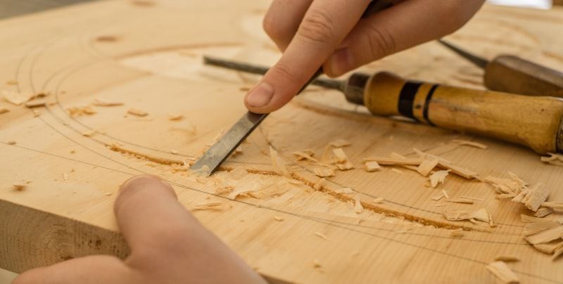 Manos reparando y tallando madera con cuidado