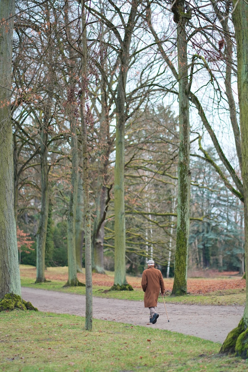 Hombre mayor caminando al aire libre por un sendero arbolado