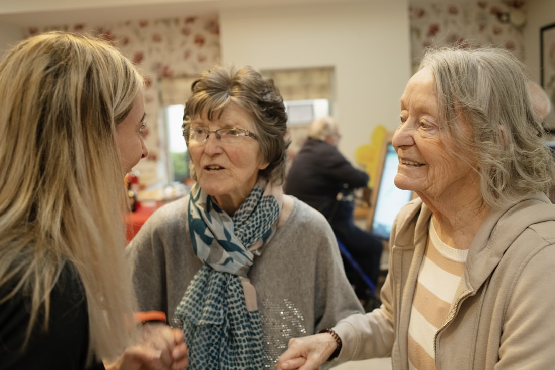 Tres mujeres mayores conversando y sonriendo con calidez