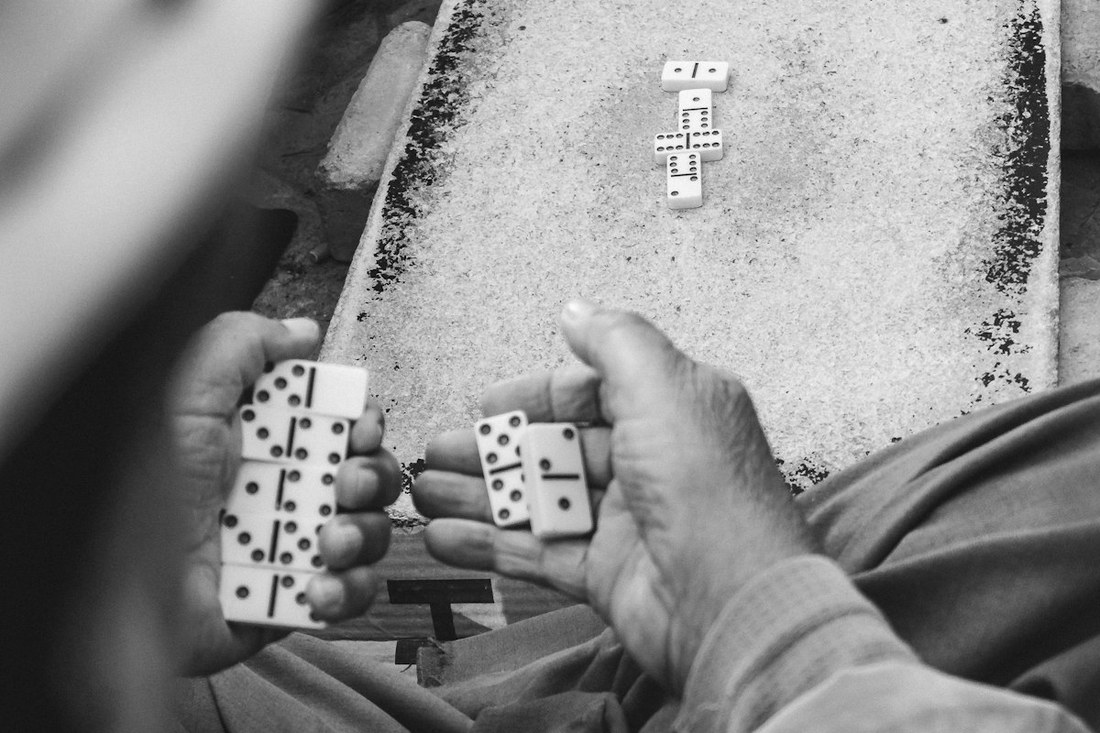 Manos jugando dominó, fichas sobre la mesa