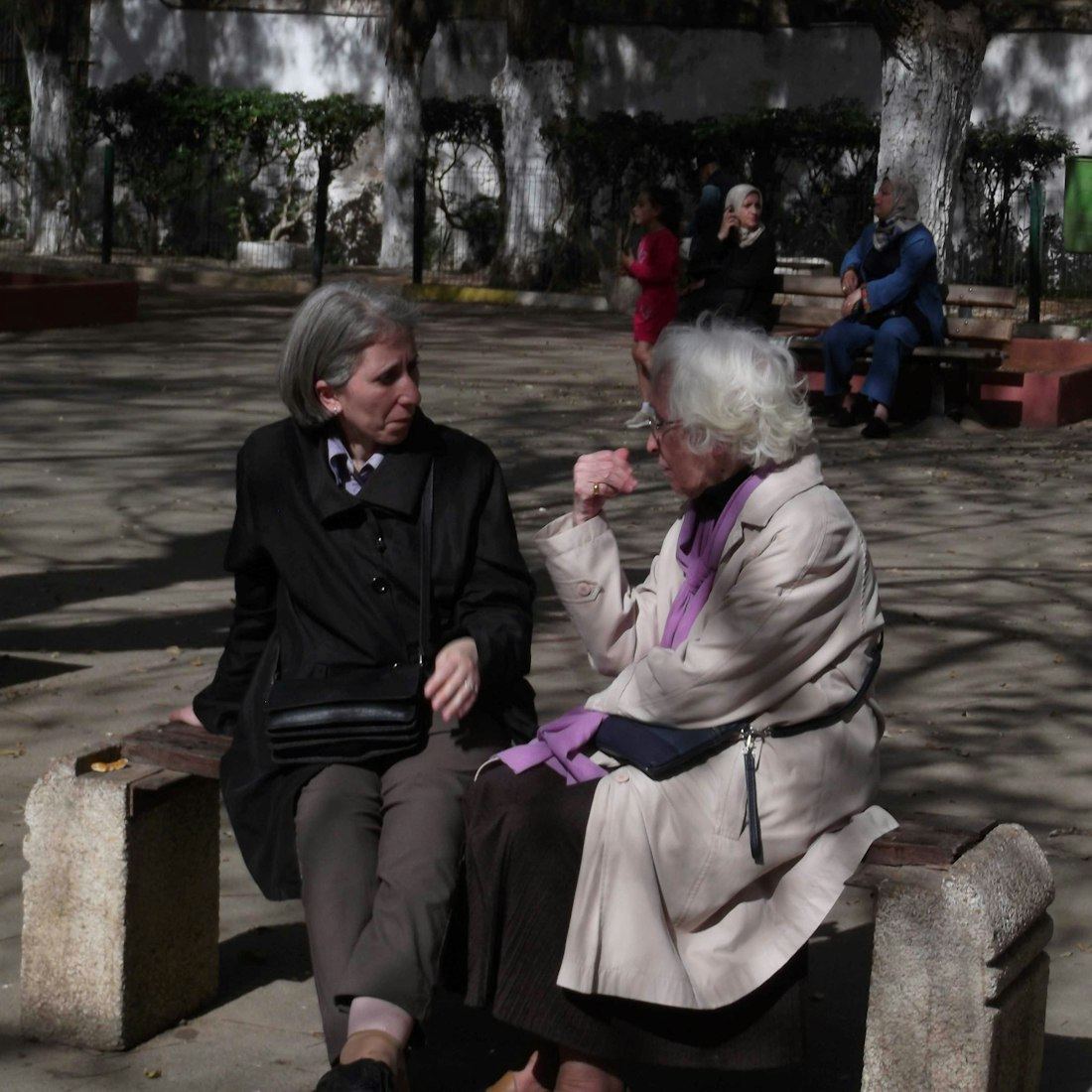 Dos amigas mayores conversando con atención y cercanía en una banca