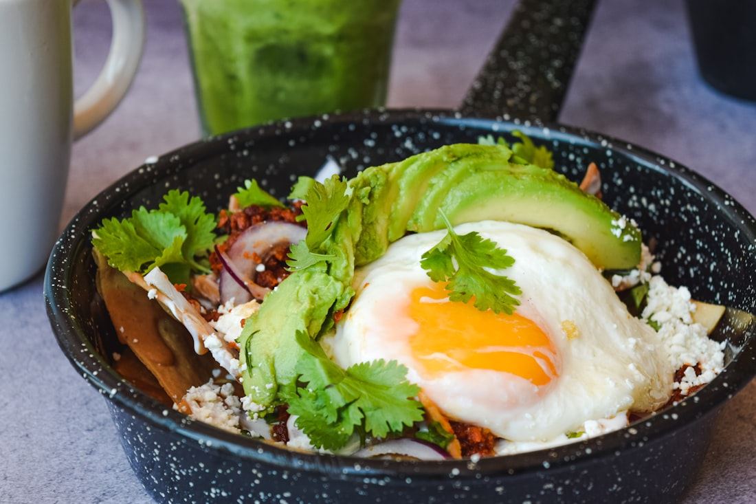Plato de huevo con aguacate, cilantro y tortilla, comida casera