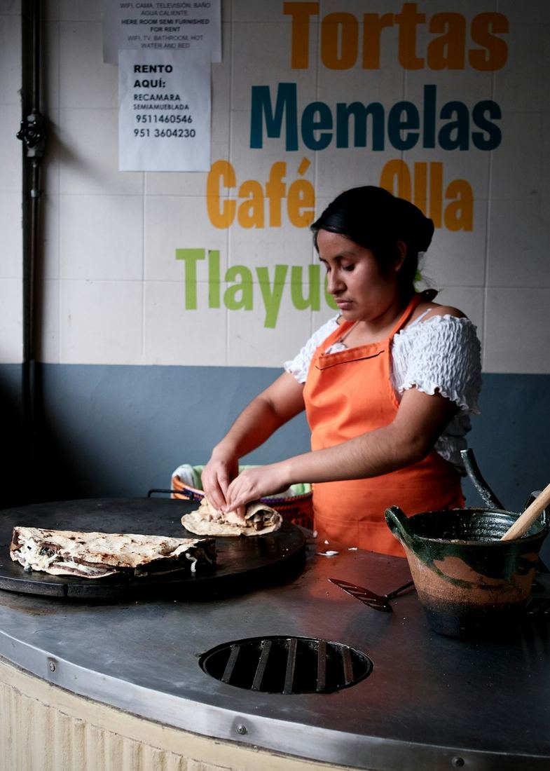 Mujer preparando comida tradicional mexicana a mano sobre un comal