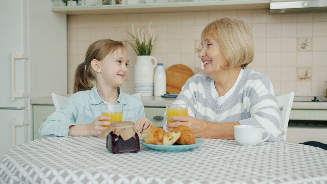 Abuela y nieta compartiendo el desayuno con cariño en la cocina