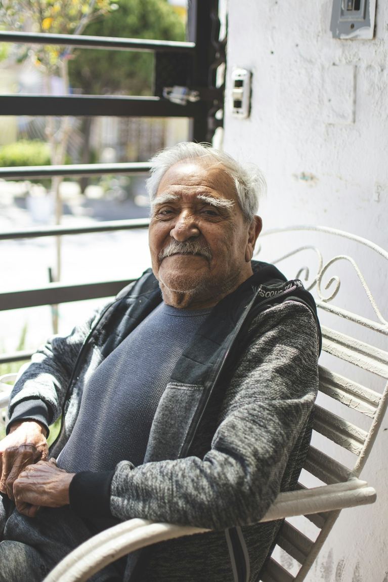 Roberto, hombre mayor mexicano, sentado con calma en el porche de su casa