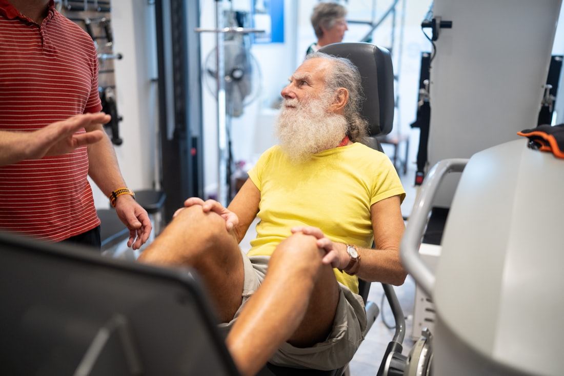 Hombre mayor entrenando la fuerza de las piernas con guía de un instructor