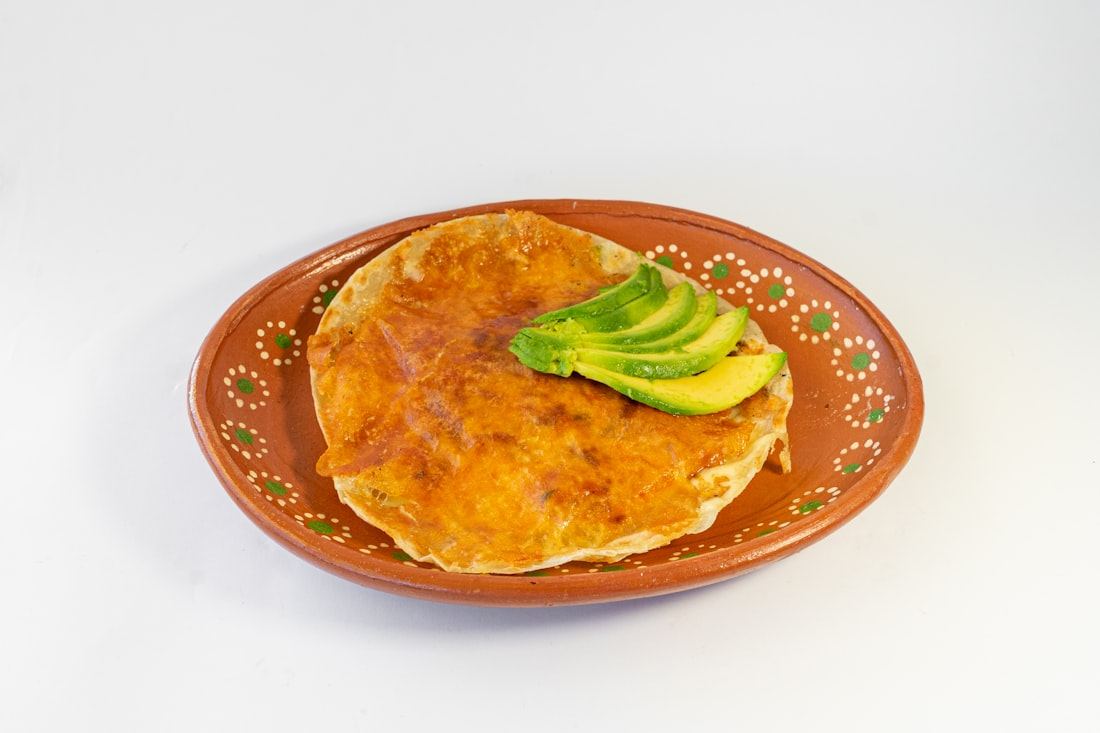 Quesadilla con aguacate servida en un plato de barro