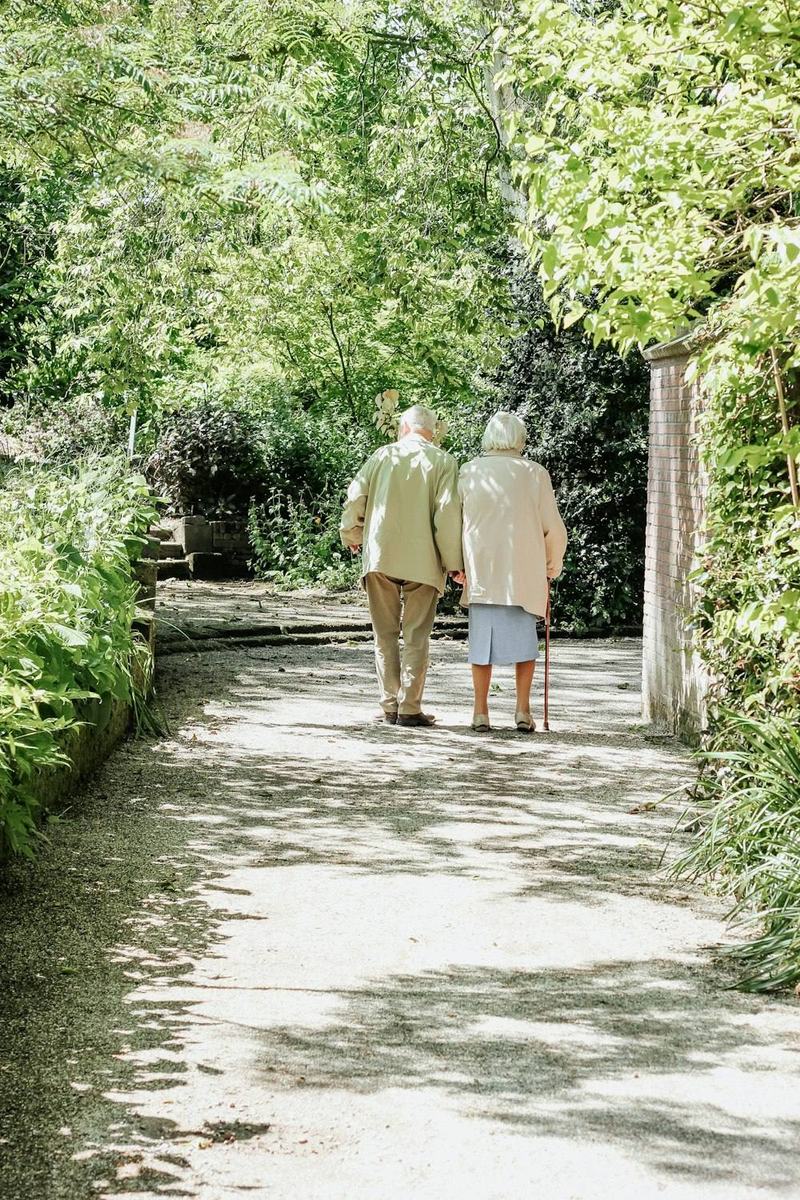 Pareja mayor caminando juntos por un sendero arbolado