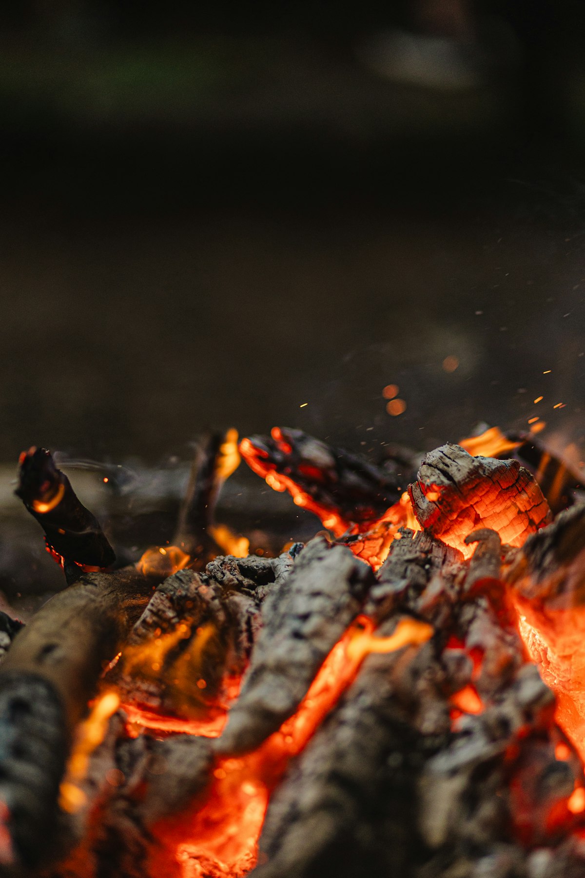 Brasas encendidas de una fogata, brillando en la oscuridad