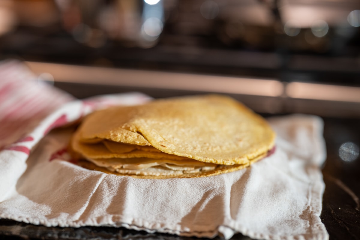 Tortillas de maíz recién hechas, apiladas sobre un paño de cocina