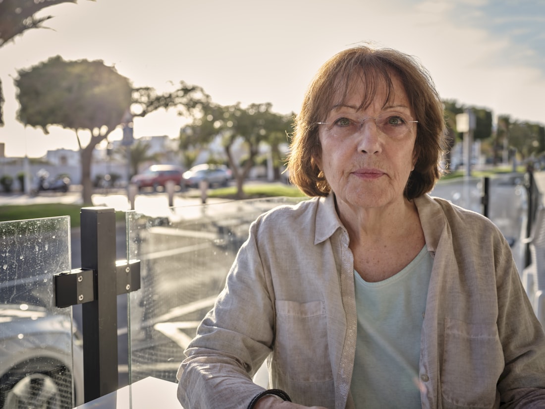 Mujer mayor sentada al aire libre, con luz de sol cálida