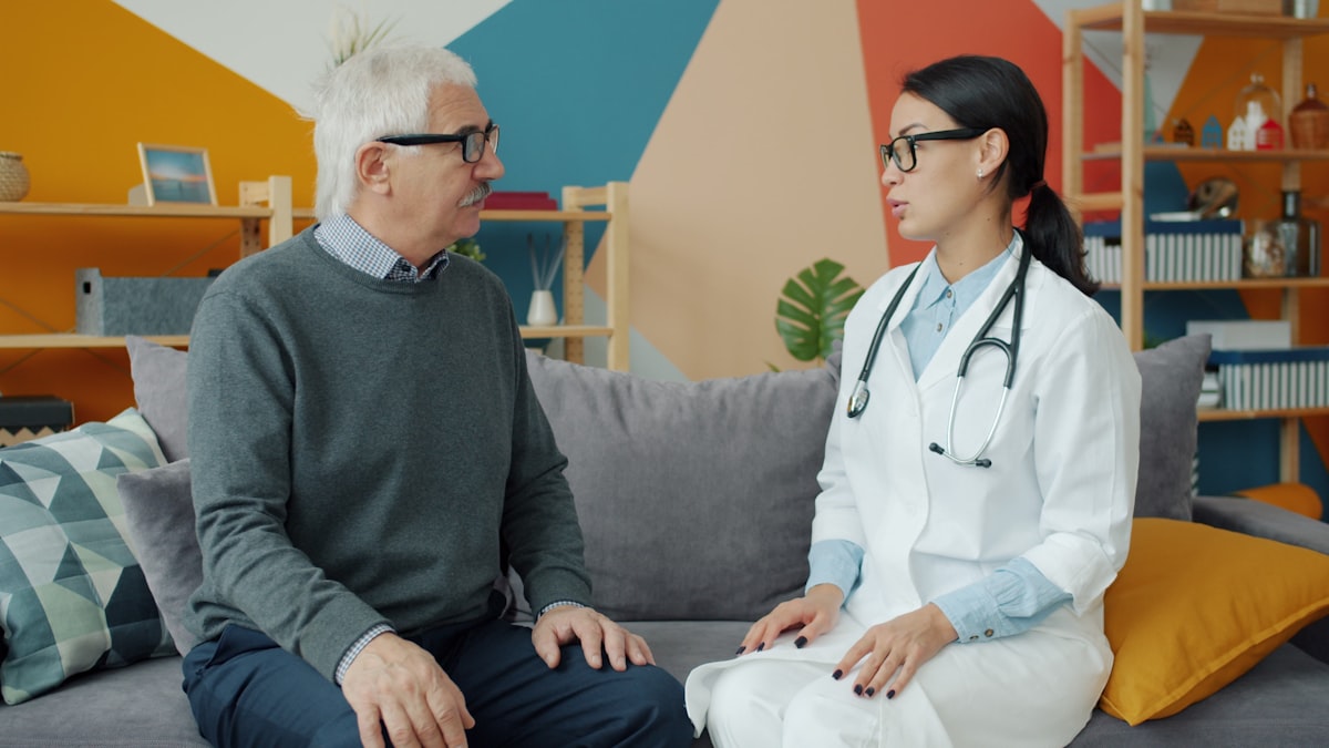 Persona mayor conversando con su médica de igual a igual, en un ambiente cálido