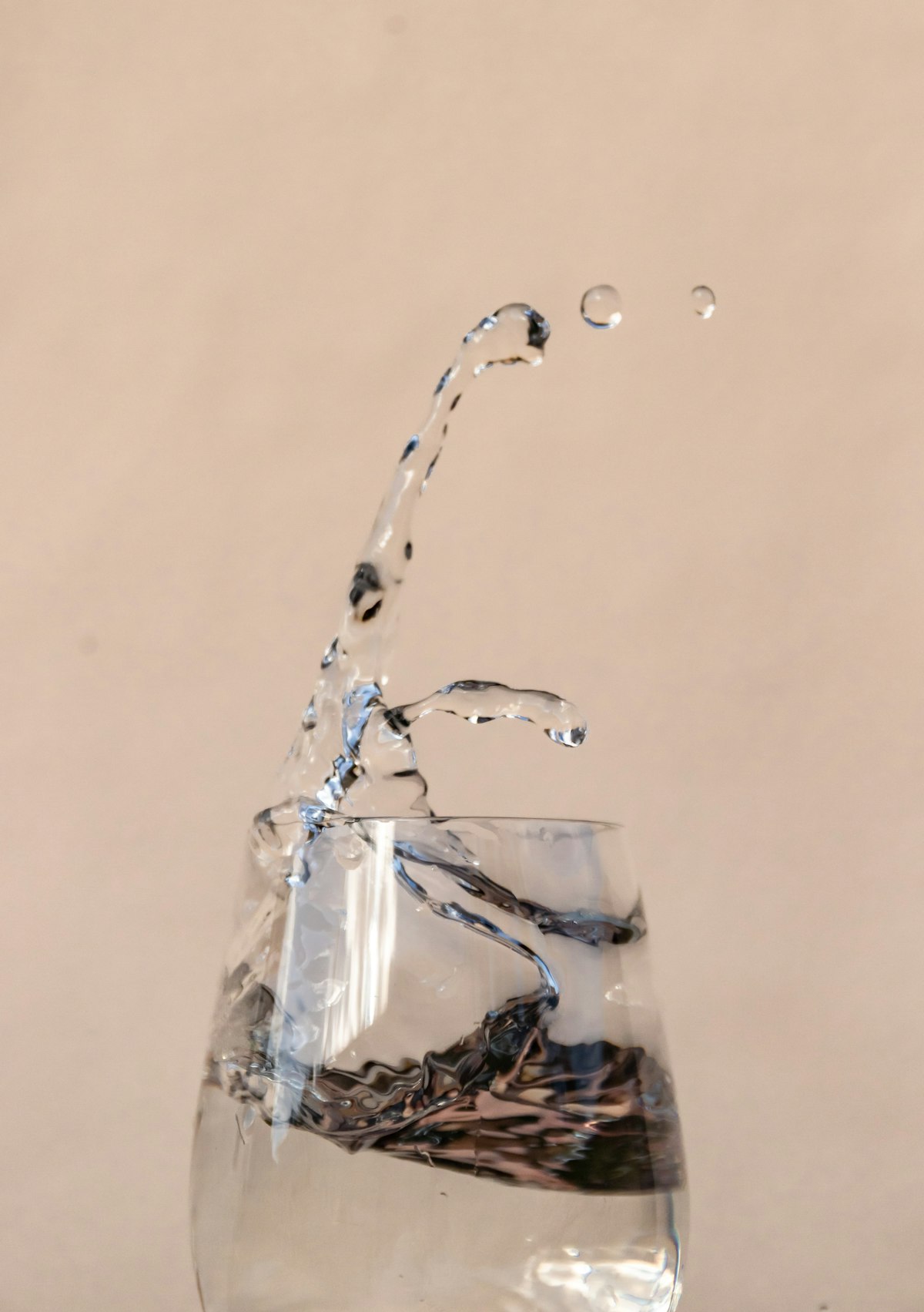 Vaso de agua transparente con un chorro de agua cayendo